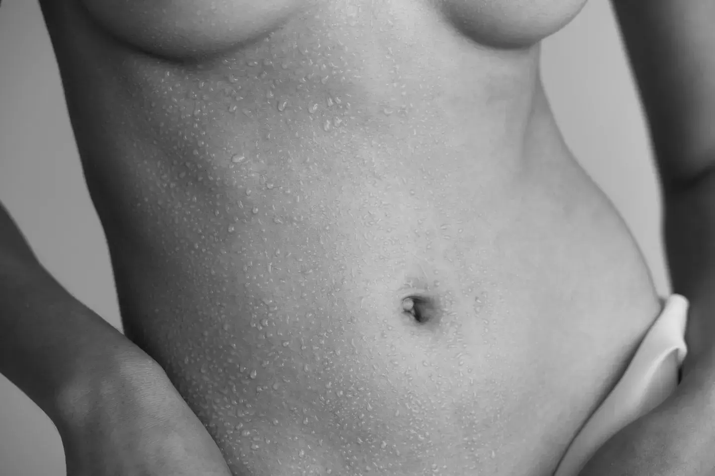 A woman 's stomach and breast in black and white.